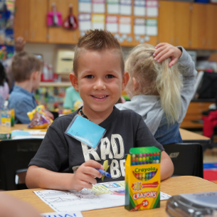 Student at desk with crayons 